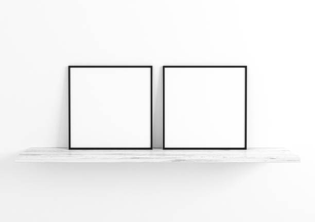 istock Double 10x10 Square Black Frame mockup on white wooden shelf and white wall. 1311164480
