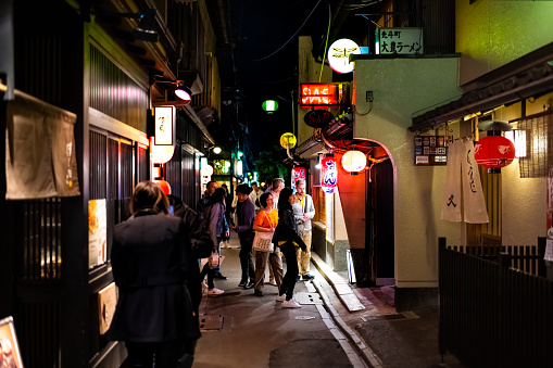 Kyoto, Japan - April 16, 2019: People walking on Pontocho alley district street at dark night with illuminated lanterns and izakaya restaurants