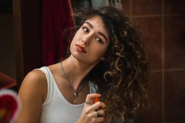 Happy young woman applying hair conditioner. Oil hair treatment for female.