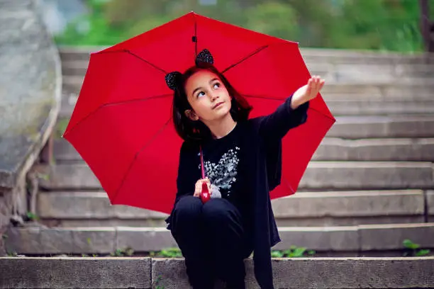 Photo of Portrait of little girl hiding from a rain