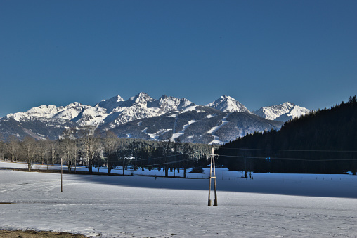 Power supply lines in front of montain range in winter in the austrian alps