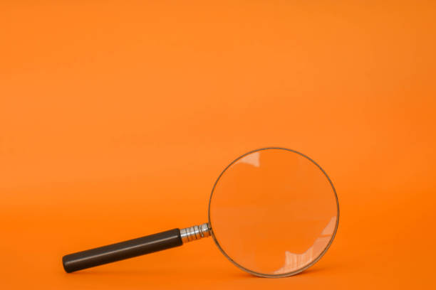 istock Magnifying glass with orange background 1311179988