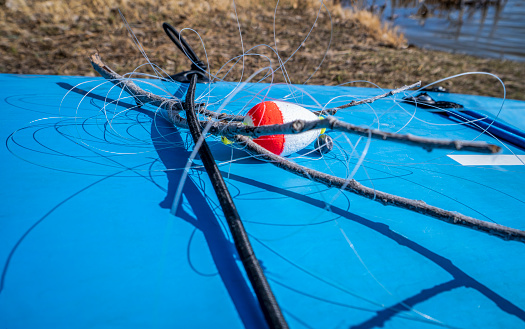 stand up paddleboard deck with a tangled fishing line retrieved by a paddler from lake to properly dispose, recreation and environmental hazard concept