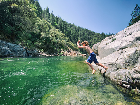 Child swims and plays in an emerald green river.