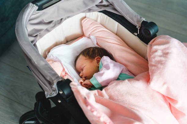 ベビーカーのゆりかごで自宅でベッドで眠っている新生児白人の赤ちゃんにクローズアップ - かわいい小さな幼児の女の子は、一日のトップビューで安らかに眠ります - ベビーカー ストックフォトと画像