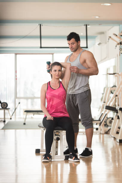 istock Gym Coach Helping Woman On Triceps Exercise 1311186023