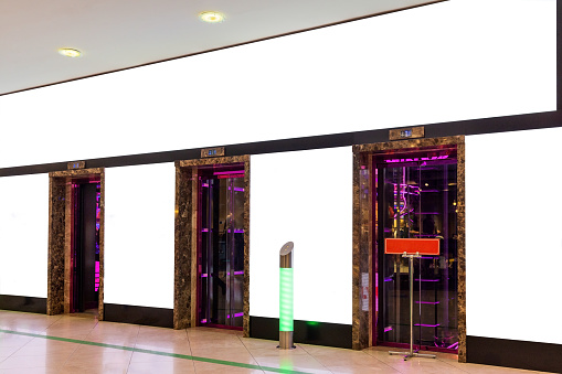 Lighting panels and blank billboard on the wall of elevator's hall of a modern building