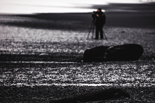 A photographer in Reynisfjara Black Sand Beach, Vik, Iceland, North Atlantic Ocean
