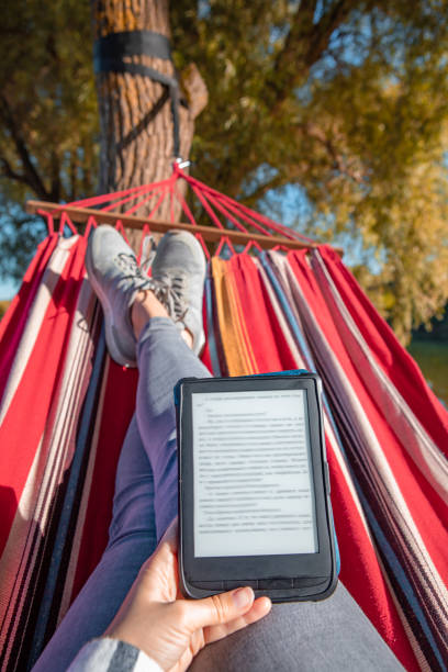 istock woman reading book laying on hammock outdoors at river beach 1311190271