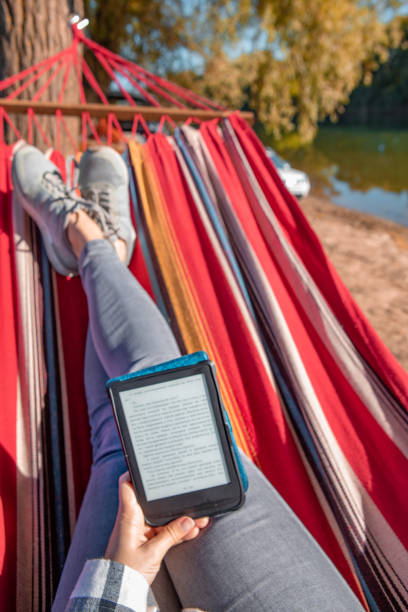 istock woman reading book laying on hammock outdoors at river beach 1311190273