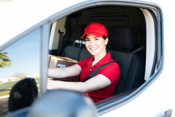 istock Happy female courier driving a white delivery van 1311192236
