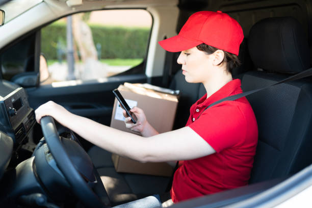 istock Young woman using a phone while driving a delivery van 1311192253