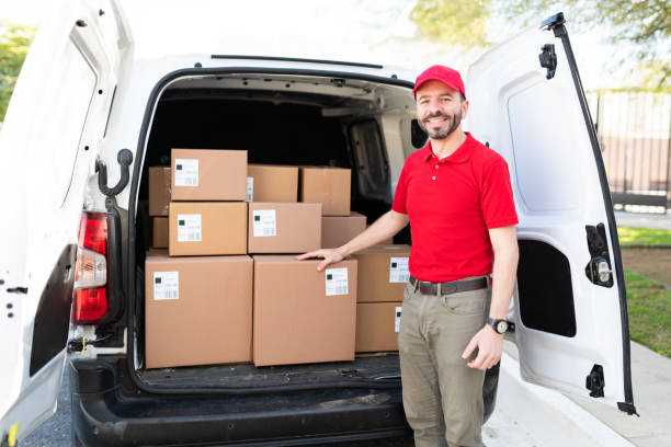 istock Male driver smiling and posing next to a delivery van 1311192268
