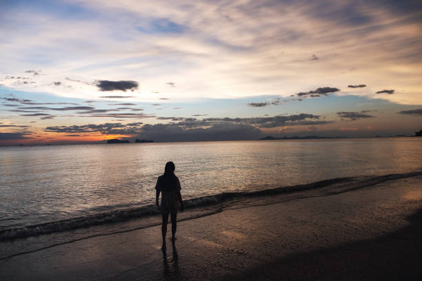istock a woman walking in the sea before sunset 1311192498