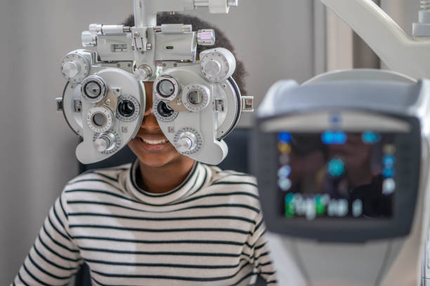 gros plan d’une adolescente africaine faisant un test oculaire sur phoropter, une adolescente africaine vérifiant son œil avec un appareil d’optométrie. - examen ophtalmologique photos et images de collection