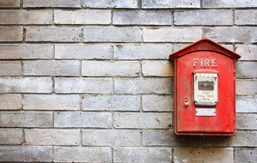 Vintage red fire alarm box on the old brick wall