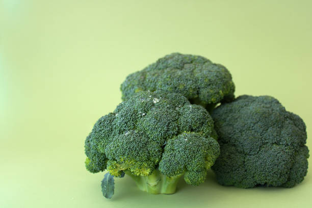 istock Vegetarian food: isolated raw broccoli on green background, copy space 1311206291