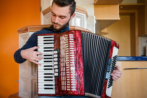 Close up of male accordionists' hands playing an accordion. Accordions are a family of box-shaped musical instruments of the bellows-driven free-reed aerophone type, colloquially referred to as a squeezebox. A person who plays the accordion is called an accordionist.