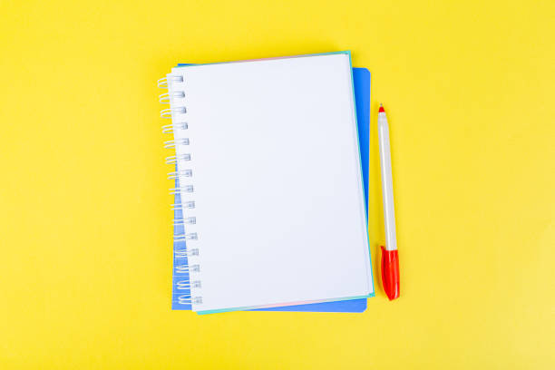 istock open spiral notepad on a yellow background with a pen. top view, stack of notepad with blank sheet. school concept, businessman work desk. 1311214757