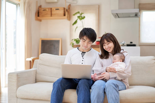 Asian family looking at a laptop on the sofa Asian family looking at a laptop on the sofa korean baby stock pictures, royalty-free photos & images