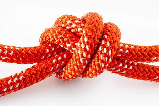Rope tie knot Closeup. Rope with a two tied knot in the middle isolated from background. A symbol of trust, strength, safety support faith and togetherness concept. Illustrative conceptual photography