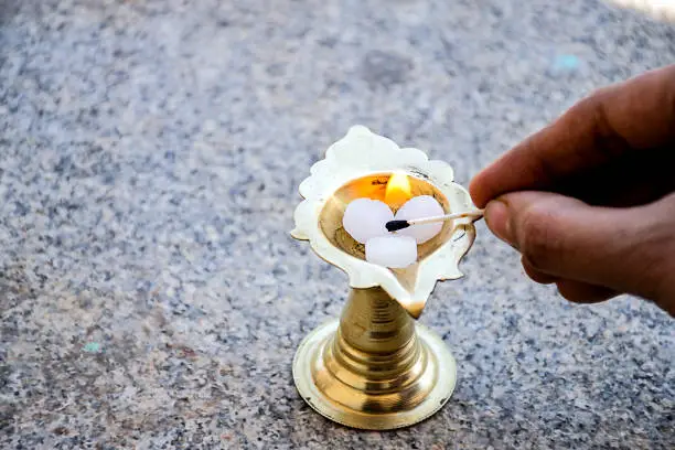 Stock photo of white camphor kept in camphor holder man lighting up camphor for presenting rituals at Bangalore Karnataka India.