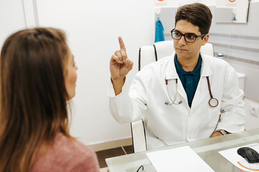 Neurologist performing neurological tests on a female patient. Neurologist holding out his finger and moving it for his patient to follow it with her eyes