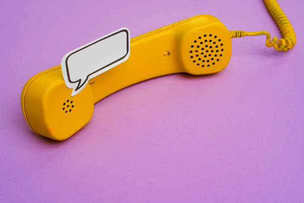 istock Yellow landline phone with speech bubble on purple background 1311223336