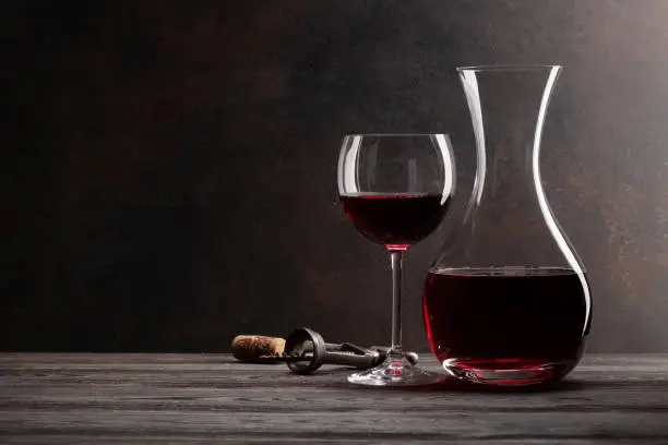 Photo of Wine decanter, glass of red wine and corkscrew