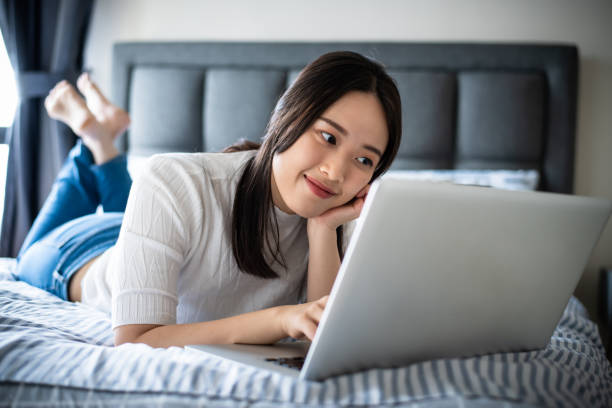 istock Young Asian woman lying on bed and using laptop. 1311225683