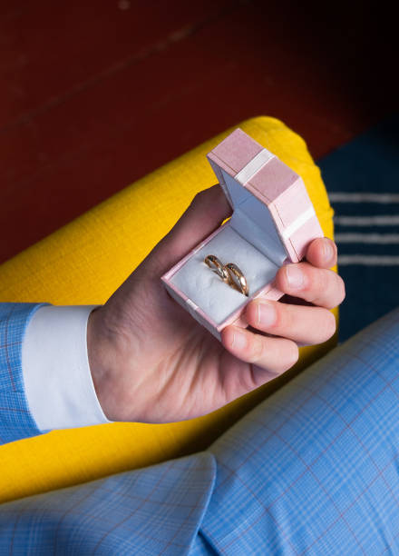 istock A man's hand holds a pink box with wedding rings 1311230140