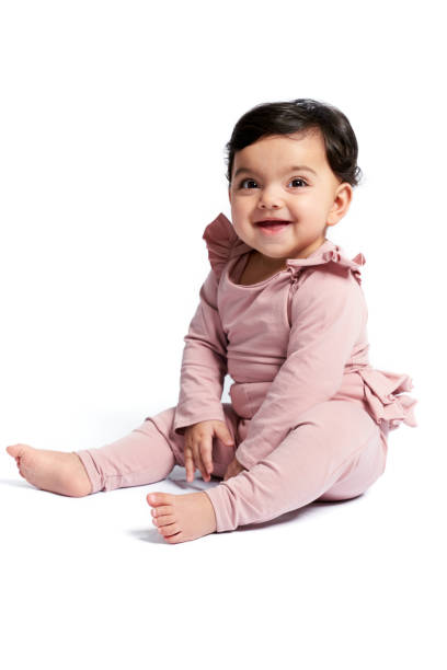 istock Smiling baby girl sitting on studio floor. 1311230262