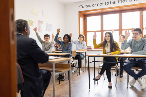 istock High school students raising hands to answer teacher's question 1311230292