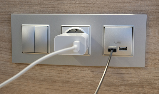 Electrical power socket, usb socket, light switch on the wood panel in the interior of the hotel. For convenience, the mobile charger or smartphone in the concept of modern life. Close up.