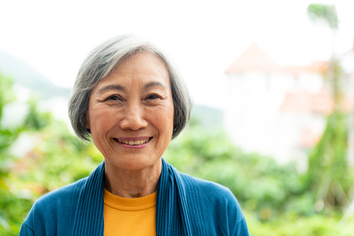 A senior woman smiling for a portrait, taken outdoors in Taipei, Taiwan.