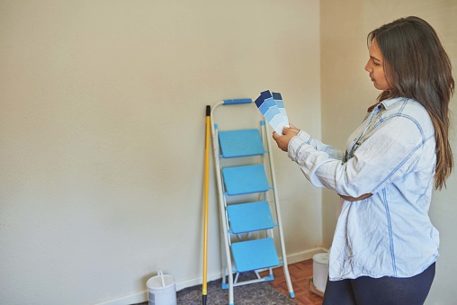 Shot of a woman looking a paint swatch before painting at home