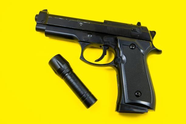 istock Black gun and flashlight lies on a yellow background. Private detectives work. Searching information concept. 1311234341
