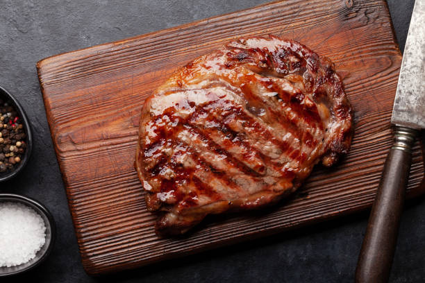 bife de carne grelhada - rib eye steak beef cutting board meat - fotografias e filmes do acervo