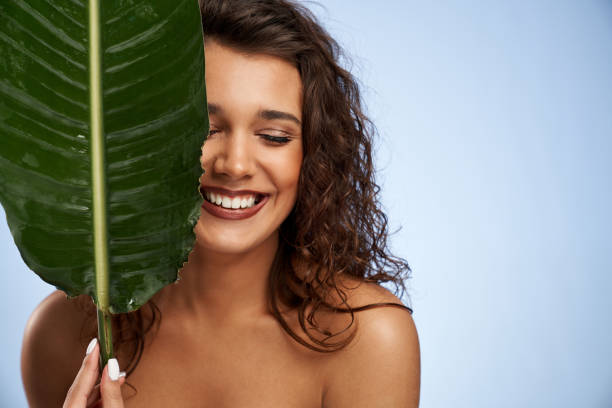 istock Naked woman laughing, hiding face behind green leaf. 1311235016