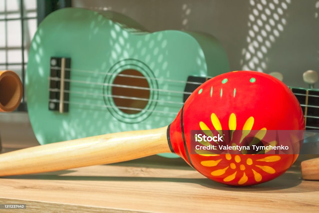 Red maracas and green small Ukulele guitar sale in music shop Red maracas and green small Ukulele guitar on wooden shelf sale in shop. Mexican traditional musical instruments set selling in music store Cinco de Mayo Stock Photo