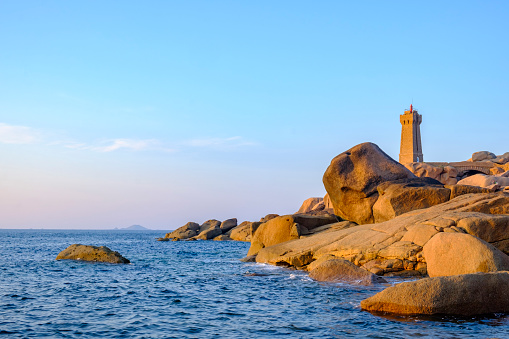 Ploumanach lighthouse or Phare de Men Ruz at the pink granite coast in Brittany, France during a beautiful summer sunset.
