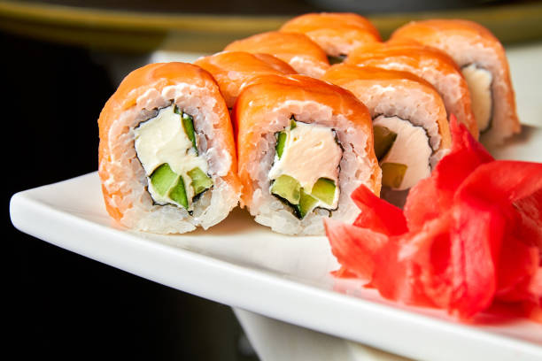 istock Rolls with salmon and cucumber, cheese and wasabi on a white plate. Closeup, selective focus 1311240089