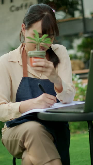 Young woman spending time to research and note on book about cactus.