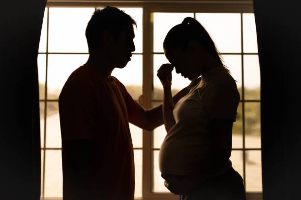 a husband comforting his stressed worried wife at home. pregnancy and relationship problems. depression. - unemployment fear depression women imagens e fotografias de stock