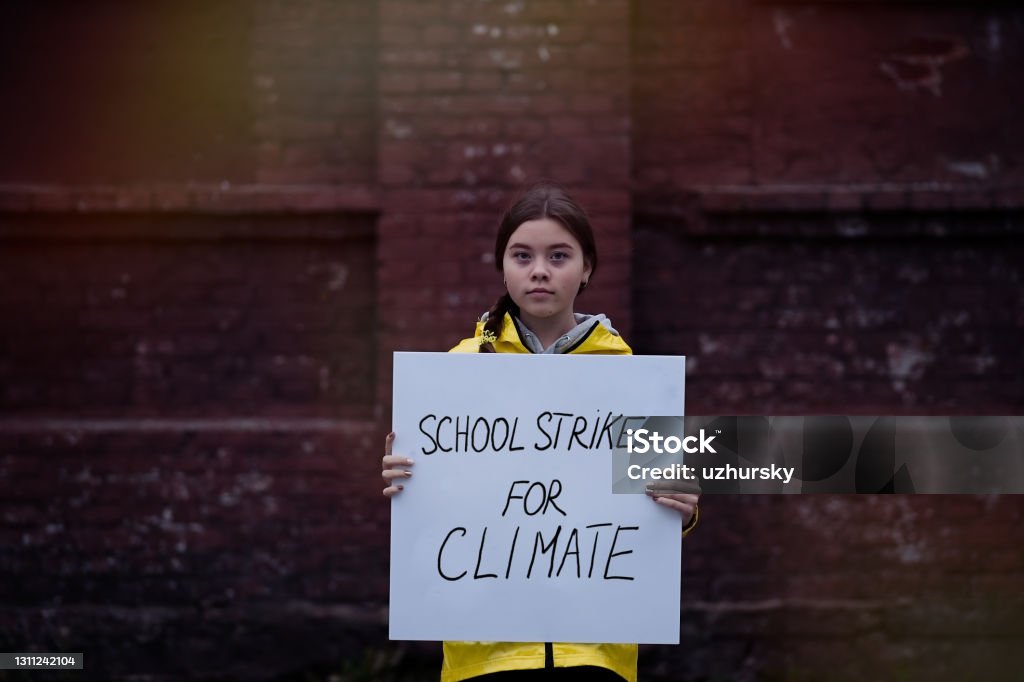 Teenage girl holding a poster on climate change Teenager girl holding placard during global strike for climate change Strike - Protest Action Stock Photo