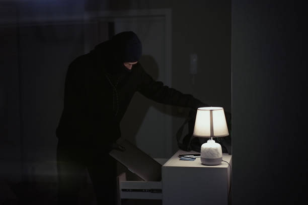 istock Burglar stealing laptop inside the house 1311242202