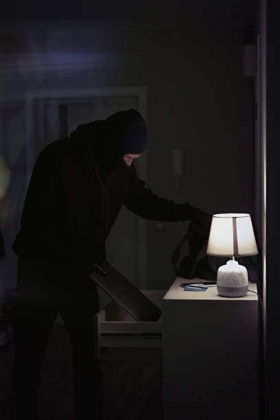 istock Burglar stealing laptop inside the house 1311242210