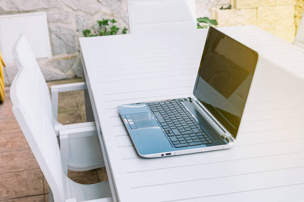 istock Open laptop on terrace table ready for teleworking, giving it yellow sunlight 1311242843
