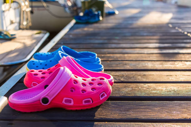 Pink and blue flip flops on the wooden pier with blurred sun glare Pink and blue flip flops on the wooden pier in early morning covered by dew with blurred sun glare on the lake on the background crocodile photos stock pictures, royalty-free photos & images