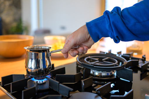 Close-up of man's hand making coffee in coffee pot in kitchen.